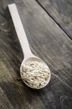 Brown rice in wooden spoon on table, close upの写真素材