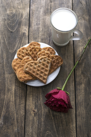 Heart shaped waffles, milk and red rose on the tableの写真素材