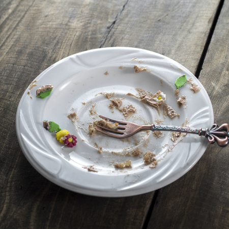 Soiled cake plate on wooden  table, close up