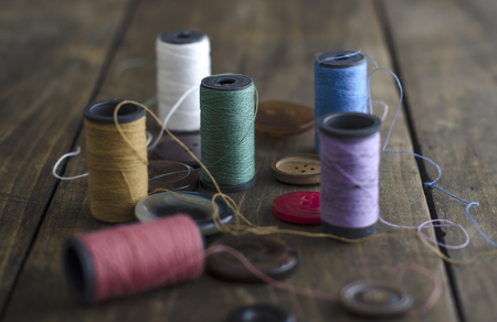 Bobbins with colorful threads on old wooden table background,