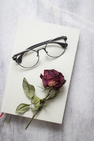 Book with beautiful  dried rose and glasses, from aboveの写真素材