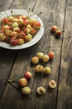 Cherries in a vintage plate with rustic wooden  backgroundの写真素材