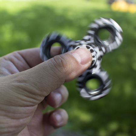 Man playing with  hand spinner fidget toy, outdoor photo