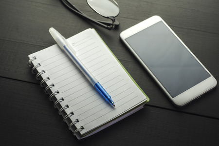 Smartphone and notebook  on dark wooden table, close upの写真素材