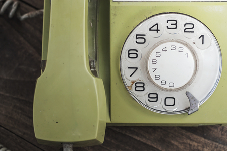 Green old-fashioned telephone on wooden background, from aboveの写真素材