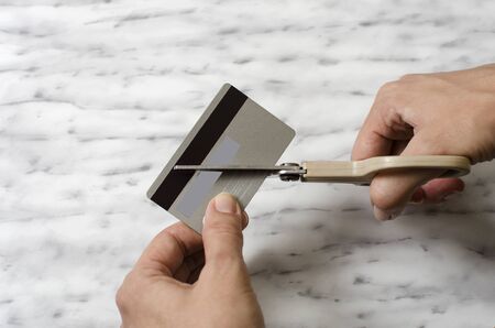 Female hands cutting credit card with scissors, close upの写真素材