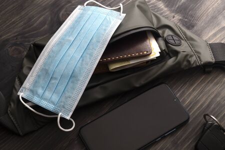 A man's everyday essentials with a  face mask, wallet and smart phone. Corona Virus Timeの写真素材