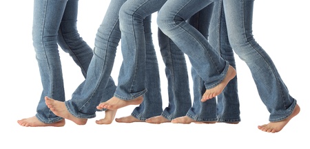 A young girls bare feet advance one step forward in jeans on whiteの写真素材
