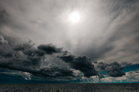 The dark sky with heavy clouds converging and a violent storm before the rain. Bad or moody weather sky and environment.の写真素材