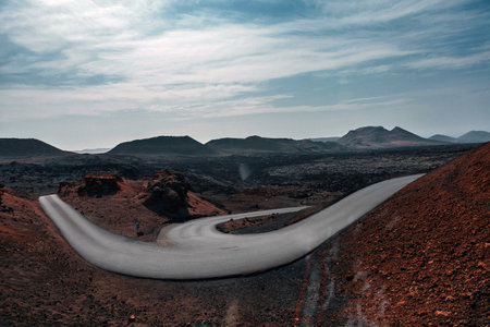 Volcanic landscapes of Lanzarote island. A road stretching into the distance. Panoramic birds-eye view of caves and cliffs, mountains.の写真素材