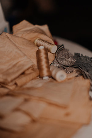 Vintage beige sewing threads on antique fabric on an old shabby desktop. manufacture of textiles or fine fabrics. industrial fabrics ,laceの写真素材