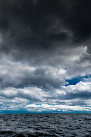 The dark sky with heavy clouds converging and a violent storm before the rain. Bad or moody weather sky and environment.の写真素材