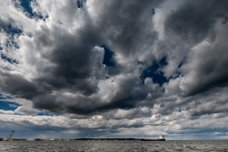 The dark sky with heavy clouds converging and a violent storm before the rain. Bad or moody weather sky and environment.の写真素材