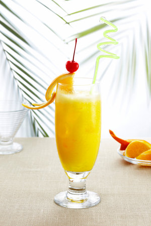 Tropical cocktail with orange and cherry on table on light backgroundの写真素材