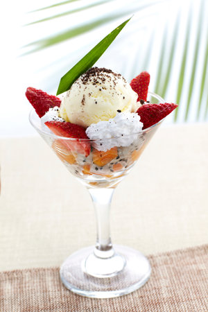 ice cream with fruits in a glass on a background of palm leavesの写真素材
