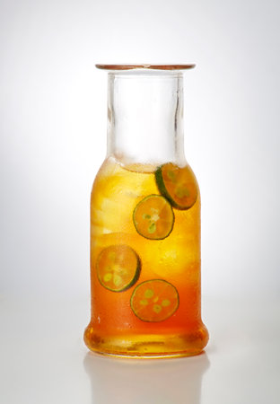 bottle of cold drink with cucumber and lime on white backgroundの写真素材