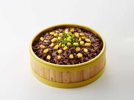Bowl of brown rice with corn on white background.の写真素材