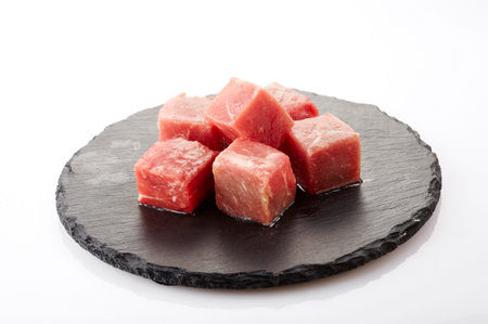 Slices of raw tuna on a black slate plate isolated on white backgroundの写真素材