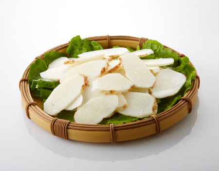 Slices of radish on salad leaf in bamboo basket on white backgroundの写真素材
