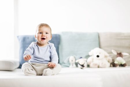 Adorable laughing baby boy sitting on sofa and looking up.の写真素材