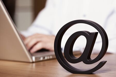 Businessman sitting at office desk working on laptop and using the internet for emailing symbolized...