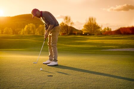 Male golf player putting at sunset.の写真素材