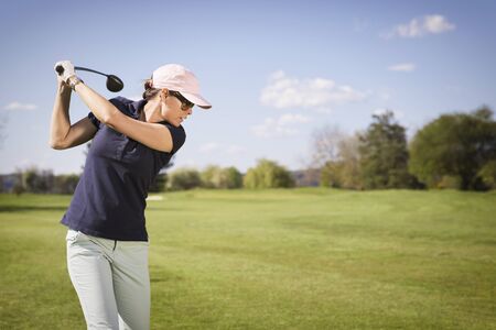 Close up of female golfer hitting golf ball.の写真素材
