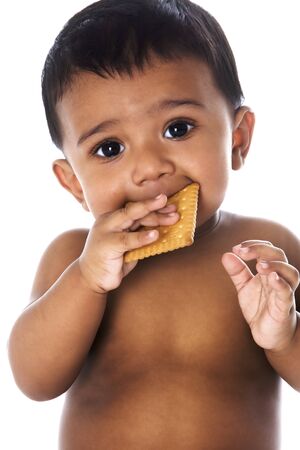 Sweet Indian baby eating a cookieの写真素材