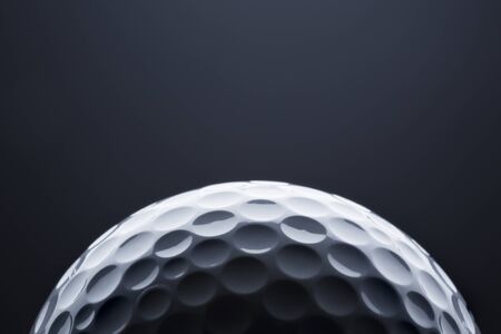 Stylish golf ball isolated on empty dark blue background, close up shot with blank space for text.の写真素材