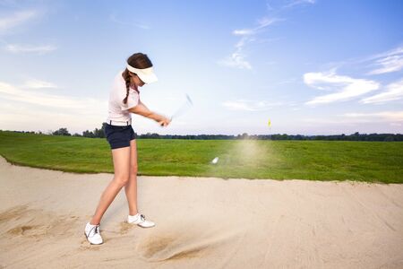 Girl golf player chipping ball in bunker.の写真素材