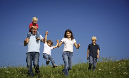 Family walking in field playing with children.の写真素材