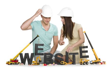Website under construction: Friendly man and woman building website-word.の写真素材