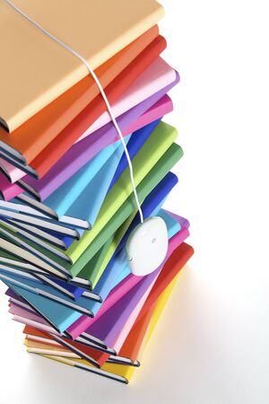 Mouse hanging from top of multi-colored book stack.の写真素材