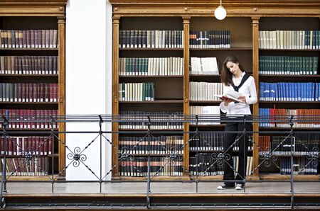 Woman reading in front of bookshelf