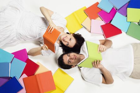 Couple lying on floor reading and looking up.の写真素材