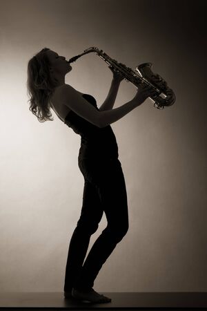 Woman playing saxophone, sepia toned.の写真素材