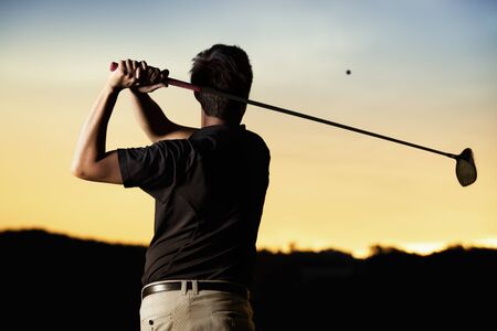 Golfer teeing off at sunset.の写真素材