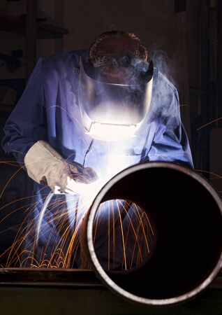 Worker welding pipe in workshop.の写真素材