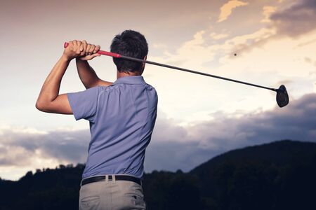 Golfer teeing off at sunset.の写真素材