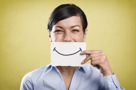 Laughing businesswoman holding empty white card in front of her mouth.の写真素材
