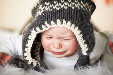 Crying baby boy with woolen cap.の写真素材