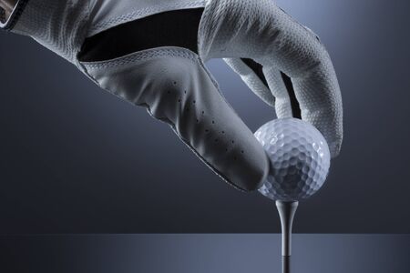 Close up of hand putting a golf ball on tee.の写真素材