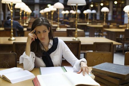 Young woman thinking in libraryの写真素材