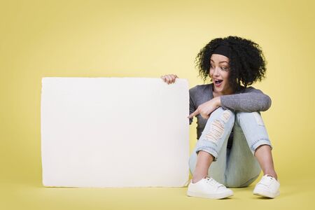 Excited woman indicating a white paper board.の写真素材