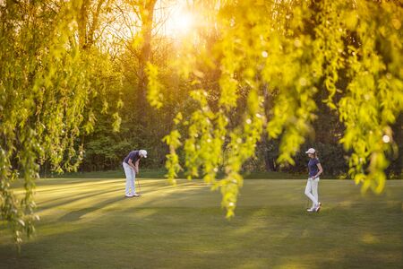 Golf player couple on green.の写真素材