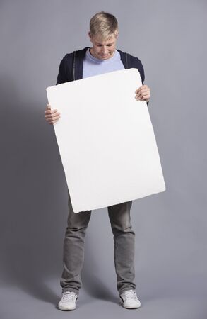 Pleased man holding white blank signboard.の写真素材