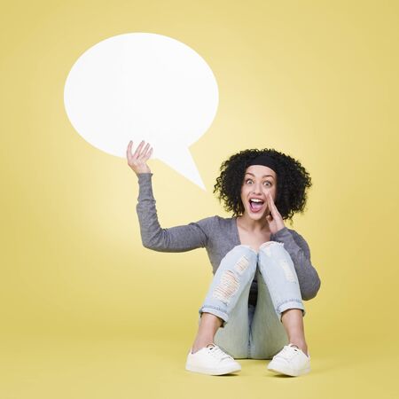 Happy girl holding a speech balloon with copy space.の写真素材