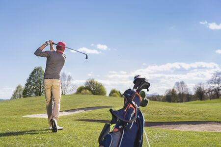 Young man playing golf on course.の写真素材