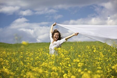 Happy woman with white piece of cloth in windの写真素材