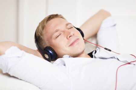 Smiling man enjoying listening music at headphones with eyes closed.の写真素材